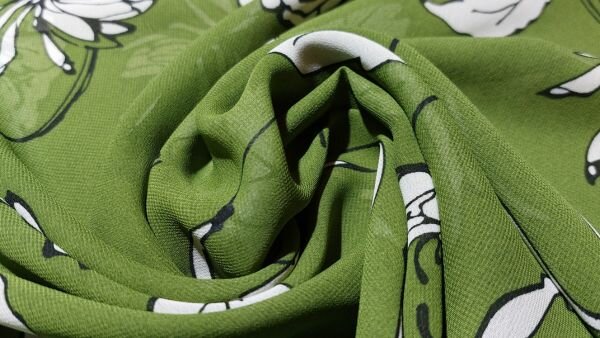 Detail bloemenprint op bosgroene voile stof