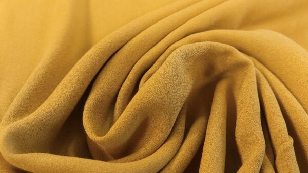 Okergele viscose cr&ecirc;pe stof close-up textuur