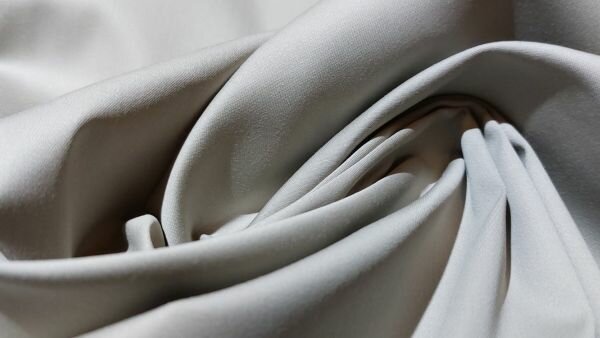 Detail van satijnbinding in lichtgrijze broekenstof