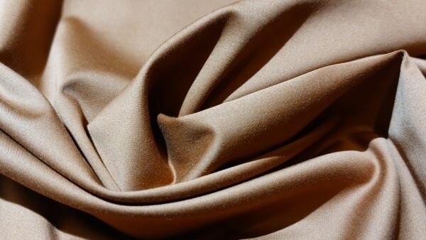 Detail van satijnbinding in bruine broekenstof	