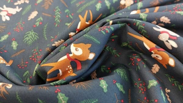 Close-up van katoenstof met hertjes en groene kersttakken op donkerblauwe achtergrond